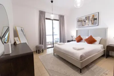a bedroom with a bed and a desk and a window at BAHAR apartments on JBR by HAPPY SEASON in Dubai