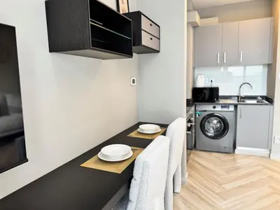 a kitchen with a table and a washing machine at Warm and Elegant Studio in Dubai in Dubai