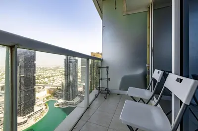 a balcony with two chairs and a view of a city at Lake Terrace I JLT I 1 Bedroom Apartment in Dubai
