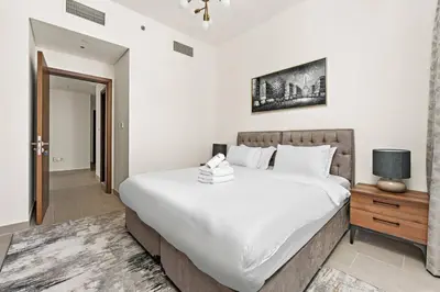 a bedroom with a large white bed and a night stand at StoneTree - Elegant 1BR in amazing community in Dubai