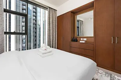 a bedroom with a white bed and a large window at StoneTree - Elegant 1BR in amazing community in Dubai