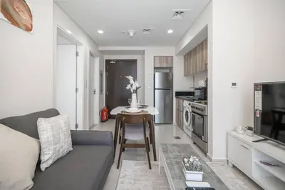 a living room with a couch and a table in a kitchen at StoneTree - Cozy 1BR with spacious balcony in Golf Vita A in Dubai
