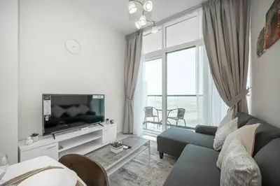 a living room with a couch and a tv at StoneTree - Cozy 1BR with spacious balcony in Golf Vita A in Dubai