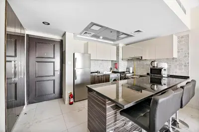 a kitchen with a stainless steel refrigerator and a counter at StoneTree - Spacious 2BR in Peaceful Community in Dubai