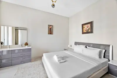 a white bedroom with a large bed and a sink at StoneTree - Spacious 2BR in Peaceful Community in Dubai