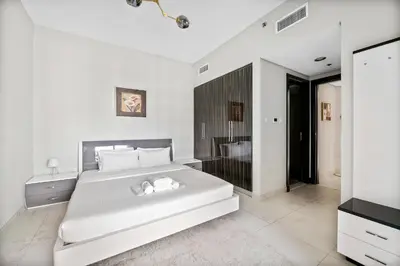 a white bedroom with a large bed and a television at StoneTree - Spacious 2BR in Peaceful Community in Dubai