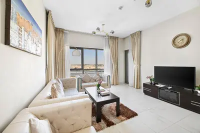 a living room with a couch and a tv at StoneTree - Spacious 2BR in Peaceful Community in Dubai