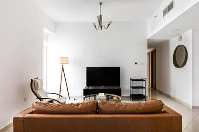 a living room with a brown couch and a tv at Tranquil Retreat With Epic Marina View in Dubai