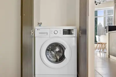 a white washer and dryer in a room at StoneTree - Stylish 1BR & Pool with Burj Khalifa Views in Dubai