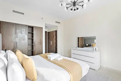 a white bedroom with a large bed and a mirror at StoneTree - Stylish 1BR & Pool with Burj Khalifa Views in Dubai