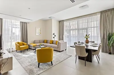 a living room with a couch and a table and chairs at StoneTree - Furnished 2 BR with Maids Room in Dubai Marina in Dubai