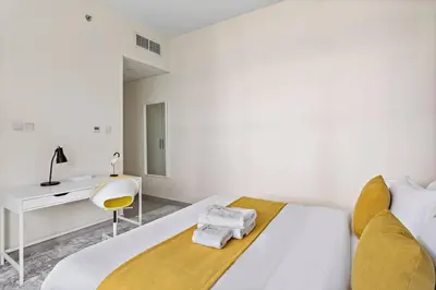 a white bedroom with a bed and a desk at StoneTree - Furnished 2 BR with Maids Room in Dubai Marina in Dubai