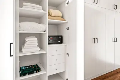 a white closet with white cabinets and a clock at Luxury apartment at Discovery in Dubai