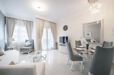 a white living room with a table and chairs at StoneTree - Furnished 1BR in Prime Location in Dubai