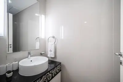 a white bathroom with a sink and a mirror at StoneTree - Furnished 1BR in Prime Location in Dubai