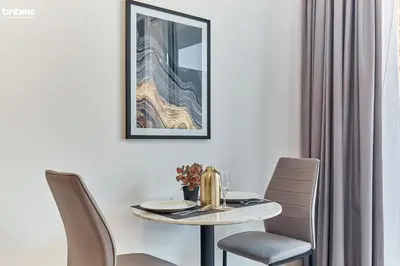 a dining room table with chairs and a picture on the wall at bnbmehomes - Luma21 in Dubai