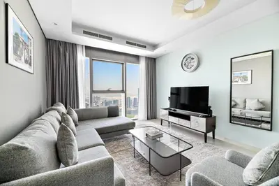 a living room with a couch and a television at StoneTree - Furnished 2 BR with City View in Dubai