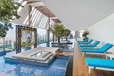 a room with blue chairs and a pool in a building at StoneTree - Furnished 2 BR with City View in Dubai