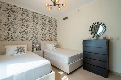 a bedroom with two beds and a mirror and a dresser at INA HOMES - 2BHK Residences Tower 1 in Dubai