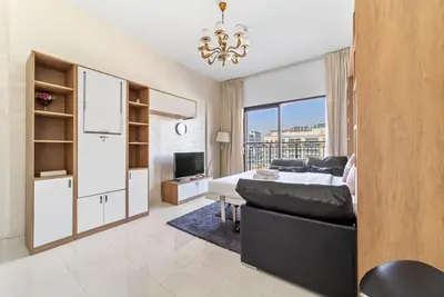 a bedroom with a bed and a living room with a tv at StoneTree - Modern Style of Studio in Resortz by Danube in Dubai
