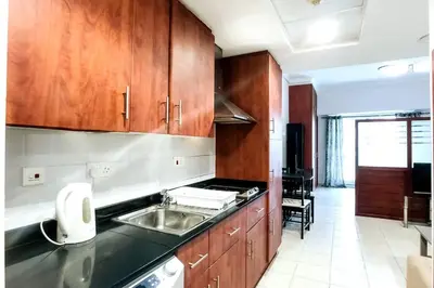 a kitchen with wooden cabinets and a sink at StoneTree - Furnished Studio with Lake View and near Metro in Dubai