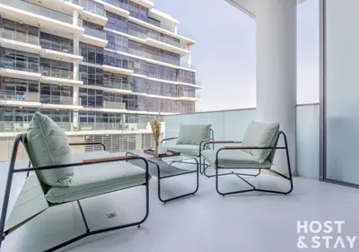 a balcony with chairs and a table and a building at Studio in Loreto 1A, DAMAC Hills - Host & Stay in Dubai