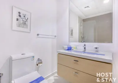 a white bathroom with a toilet and a sink at Studio in Loreto 1A, DAMAC Hills - Host & Stay in Dubai
