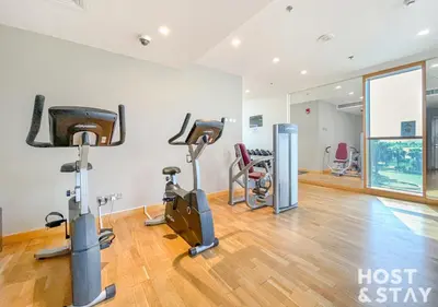a gym with treadmills and exercise bikes in a room at Studio in Loreto 1A, DAMAC Hills - Host & Stay in Dubai