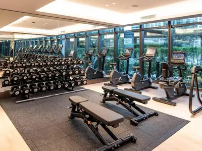 a gym with rows of exercise equipment and windows at Prime Retreats @ Address Residence Opera By Emaar in Dubai