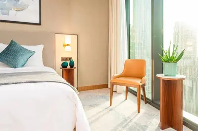 a bedroom with a bed and a chair and a window at Prime Retreats @ Address Residence Opera By Emaar in Dubai