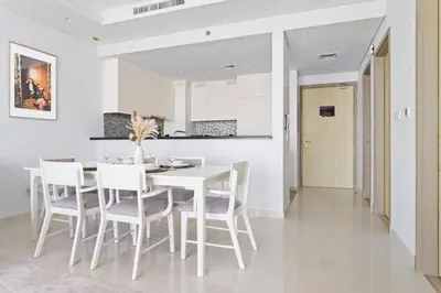 a white dining room with a white table and chairs at StoneTree - Furnished 2BR with Luxurious Style in Dubai