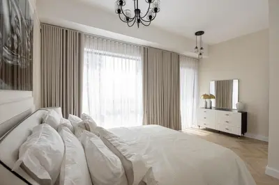 a white bedroom with a large bed and a chandelier at Beautiful stylish 1 bedroom by the JBR beach ! in Dubai