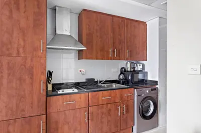 a kitchen with wooden cabinets and a washing machine at StoneTree - Stylish Studio near Metro Station in Dubai