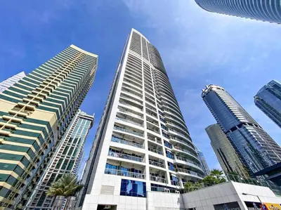 two tall buildings with palm trees in front of a blue sky at StoneTree - Stylish Studio near Metro Station in Dubai