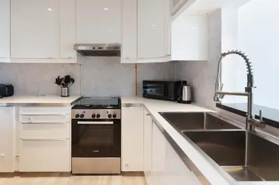 a kitchen with white cabinets and a sink and a stove at Plaza Residences - 2BR Apartment - Allsopp&Allsopp in Dubai
