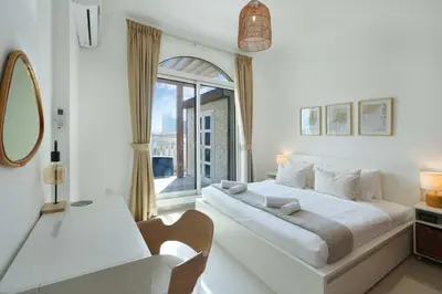 a white bedroom with a large bed and a window at Plaza Residences - 2BR Apartment - Allsopp&Allsopp in Dubai