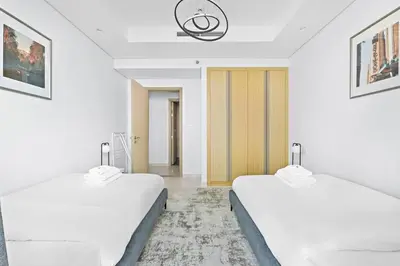 two beds in a room with white walls at StoneTree - Luxurious 2 BR Apartment with Stunning View in Dubai