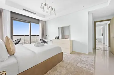 a white bedroom with a large bed and a desk at StoneTree - Luxurious 2 BR Apartment with Stunning View in Dubai