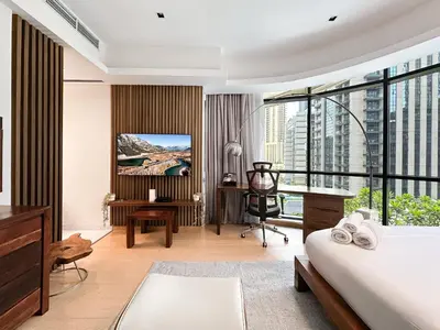 a hotel room with a bed and a desk and a tv at Trophy - Private Office Solace Suite in Dubai