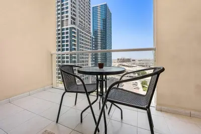 a table and chairs in a balcony with a view of a city at StoneTree - Furnished Studio Near Metro in Dubai