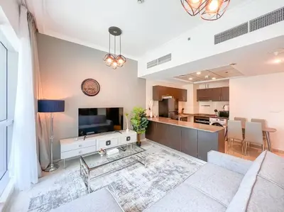 a living room with a couch and a tv and a kitchen at StoneTree - Furnished 1BR near Marina Walk in Dubai