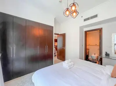 a bedroom with a large white bed and wooden cabinets at StoneTree - Furnished 1BR near Marina Walk in Dubai
