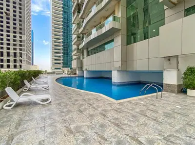 a building with a swimming pool and chairs in front of it at StoneTree - Homelike 1BR in Dubai Marina in Dubai
