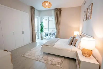 a white bedroom with a large bed and a living room at Daniels Spacious 1BR in Heart of Dubai Marina in Dubai