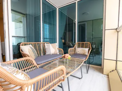 a balcony with wicker chairs and a glass table at Daniels Spacious 1BR in Heart of Dubai Marina in Dubai