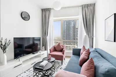 a living room with a blue couch and a large window at StoneTree - Stylish 1BR in JLT in Dubai