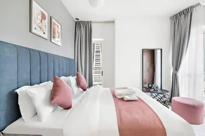 a bedroom with a large white bed with pink pillows at StoneTree - Stylish 1BR in JLT in Dubai
