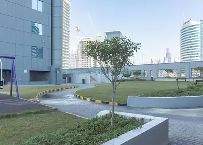 a tree in a park in front of a building at StoneTree - Cozy Studio Apartment in Business Bay in Dubai