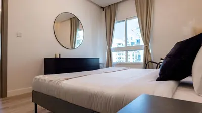 a bedroom with a large bed and a mirror at Classy 1 BR Apartment in Greens in Dubai