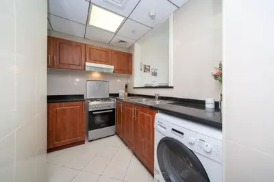 a kitchen with wooden cabinets and a dishwasher at StoneTree - Chic Studio in Jumeirah Lake Towers in Dubai
